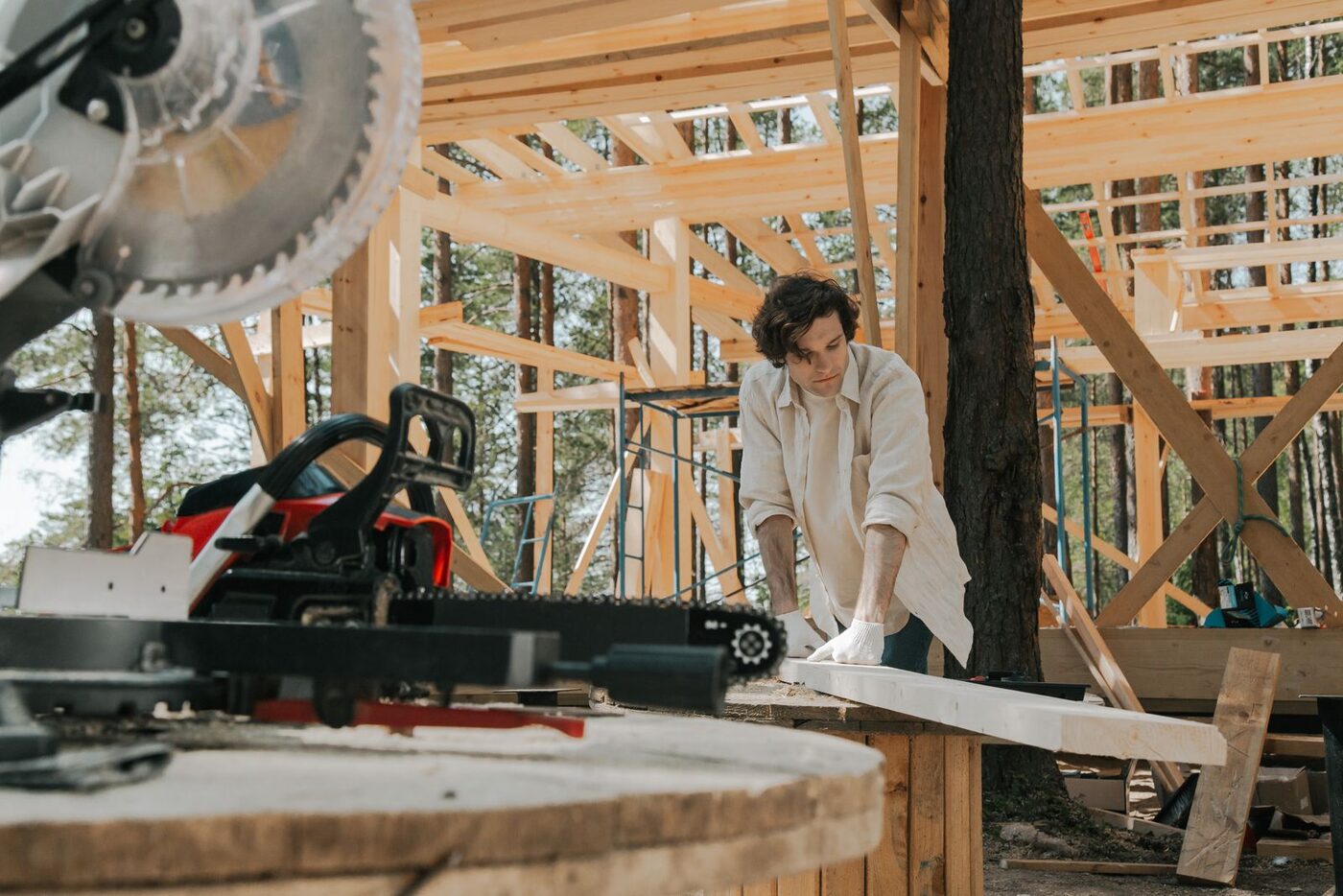 Builder working on a timber frame with a circular saw in the foreground