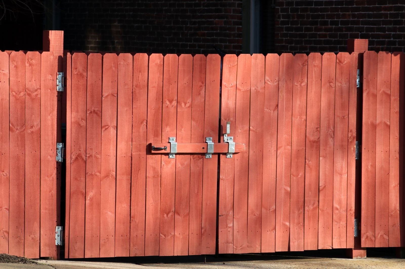 Stained timber panel fence with a steel latch on a residential boundary